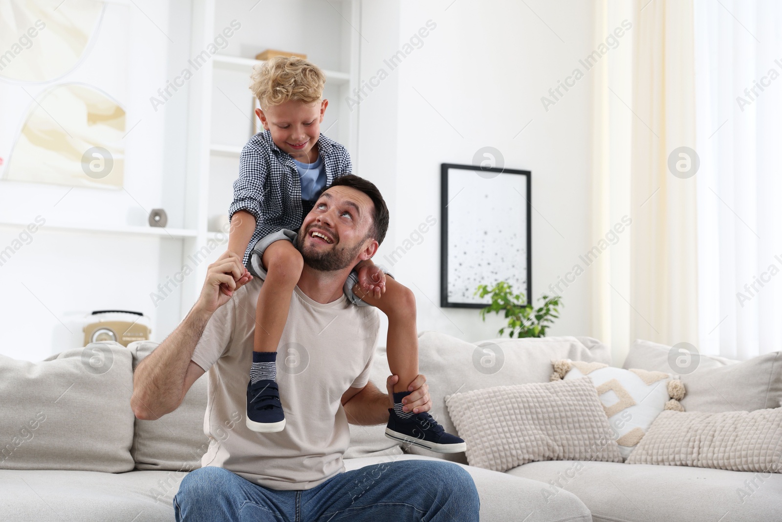 Photo of Happy father and his son spending time together on sofa at home. Family