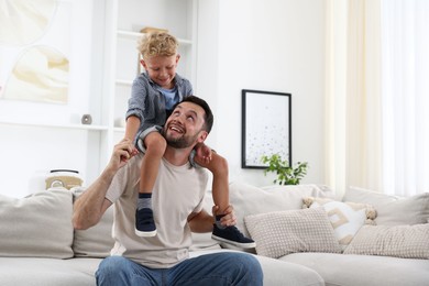 Photo of Happy father and his son spending time together on sofa at home. Family