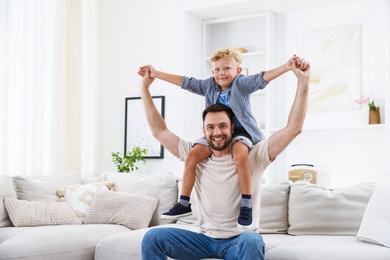 Photo of Happy father and his son spending time together on sofa at home. Family