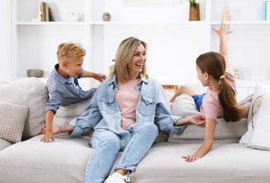 Photo of Happy mother and her children having fun on sofa at home. Family