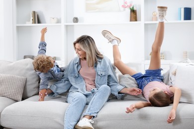 Photo of Happy mother and her children having fun on sofa at home. Family