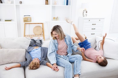Photo of Happy mother and her children having fun on sofa at home. Family