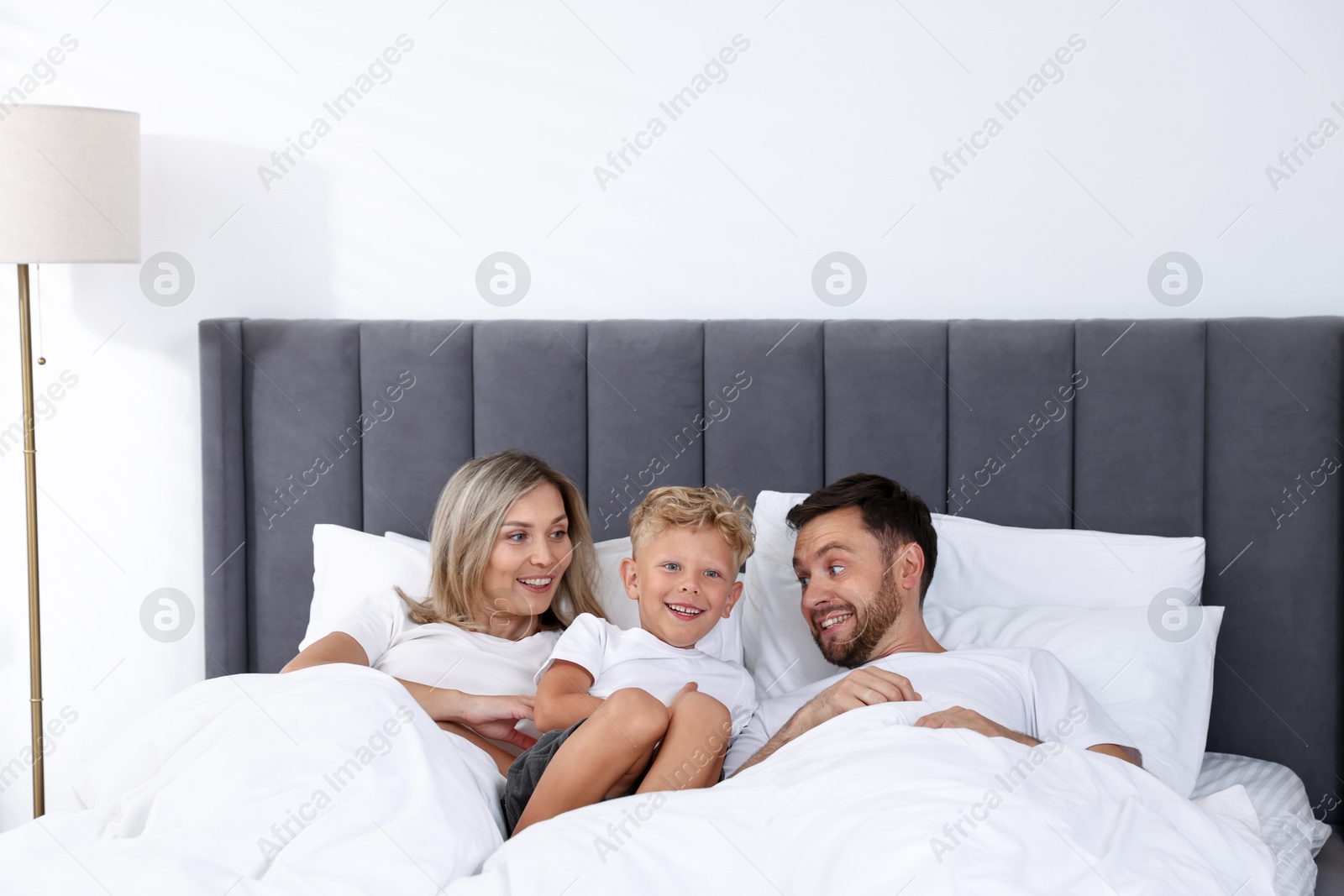 Photo of Happy family spending time together on bed at home