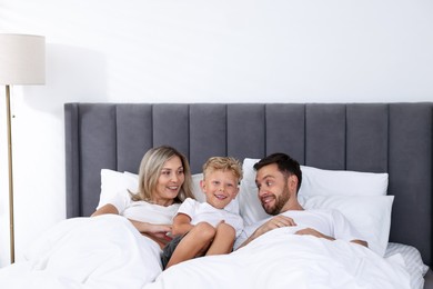 Photo of Happy family spending time together on bed at home