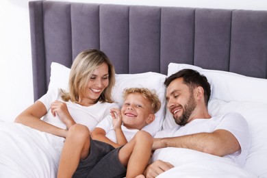 Photo of Happy family spending time together on bed at home