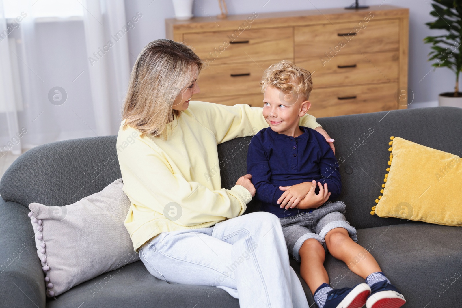 Photo of Happy mother and her son on sofa at home. Family