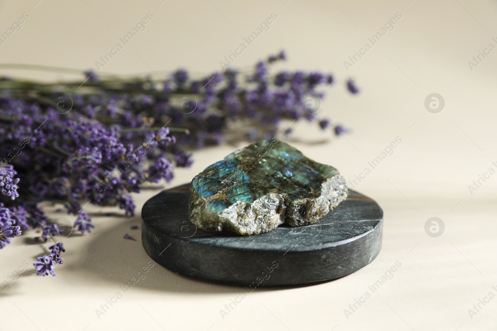 Aura. Beautiful labradorite and lavender flowers on beige background, closeup Photo of Aura. Beautiful labradorite and lavender flowers on beige background, closeup