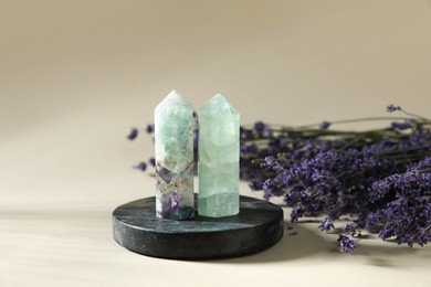 Photo of Aura. Different crystals and lavender flowers on beige background, closeup