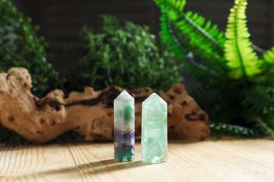 Photo of Aura. Beautiful crystals, driftwood and green plants on wooden surface