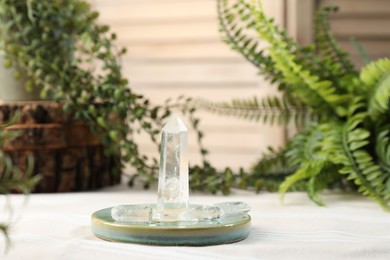 Photo of Aura. Beautiful crystals on beige fabric and green plants indoors