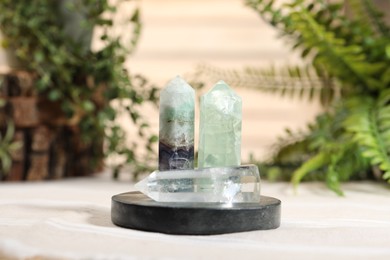 Photo of Aura. Beautiful crystals on beige fabric and green plants indoors