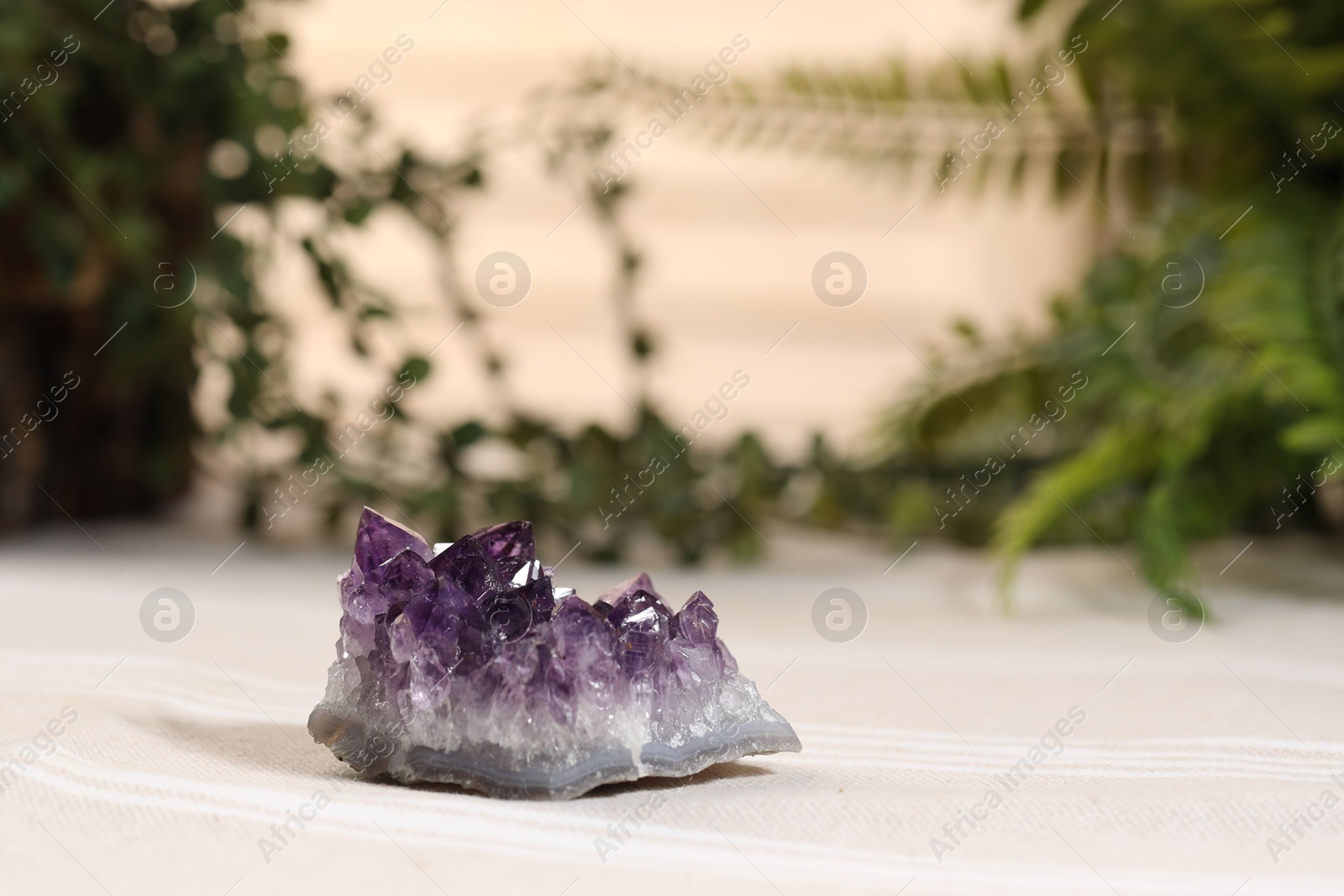 Photo of Aura. Beautiful amethyst on beige fabric indoors