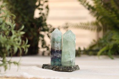 Photo of Aura. Beautiful crystals on beige fabric and green plants indoors