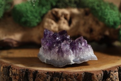 Photo of Aura. Beautiful amethyst on stump against blurred background, closeup