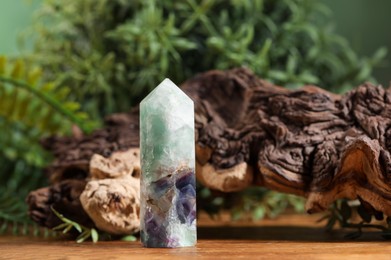 Photo of Aura. Beautiful crystal, driftwood and green plants on wooden surface