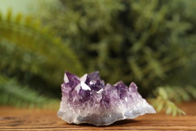 Photo of Aura. Beautiful amethyst on wooden surface against blurred green background