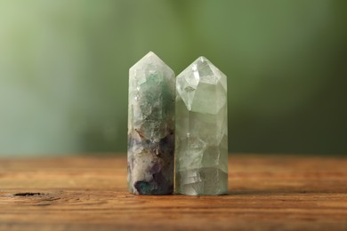 Photo of Aura. Beautiful crystals on wooden surface against blurred green background