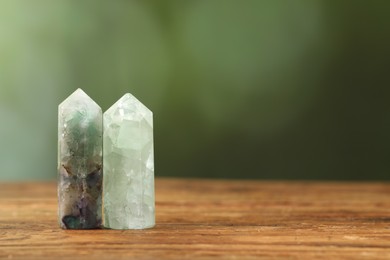 Photo of Aura. Beautiful crystals on wooden surface against blurred green background. Space for text