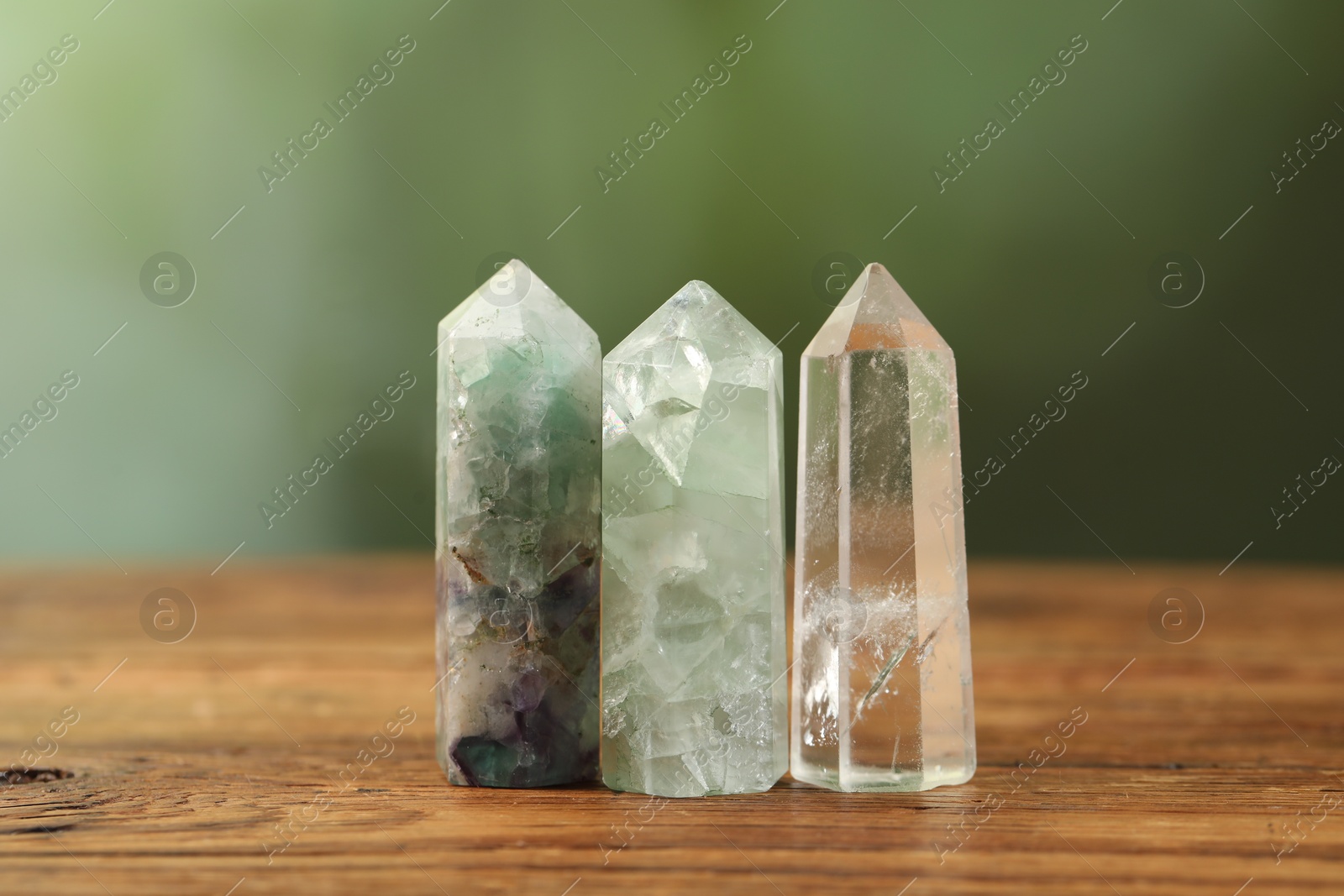 Photo of Aura. Beautiful crystals on wooden surface against blurred green background