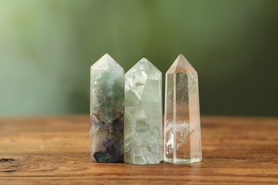 Photo of Aura. Beautiful crystals on wooden surface against blurred green background