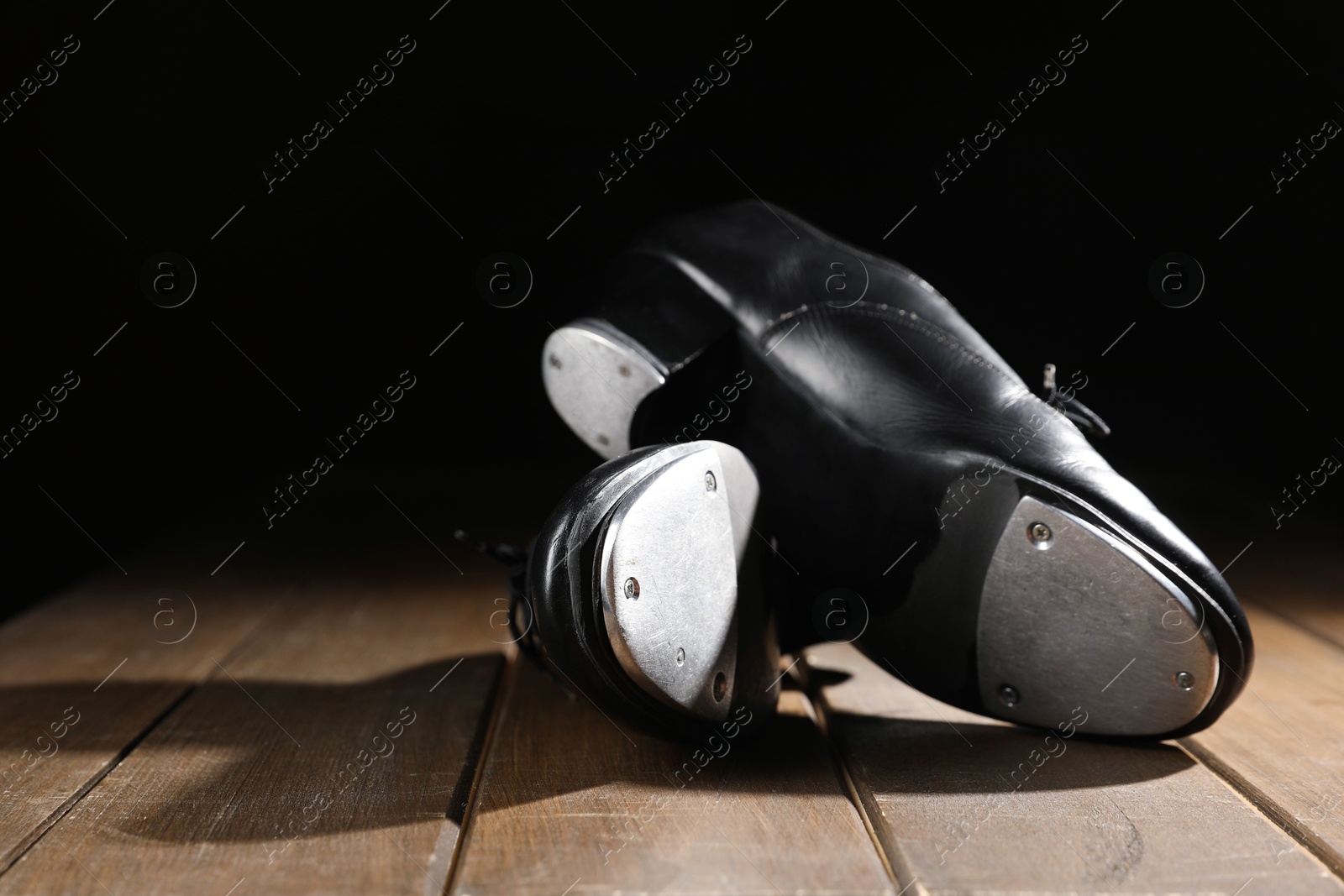Pair of tap shoes on wooden floor against black background, closeup. Tap dance Photo of Pair of tap shoes on wooden floor against black background, closeup. Tap dance