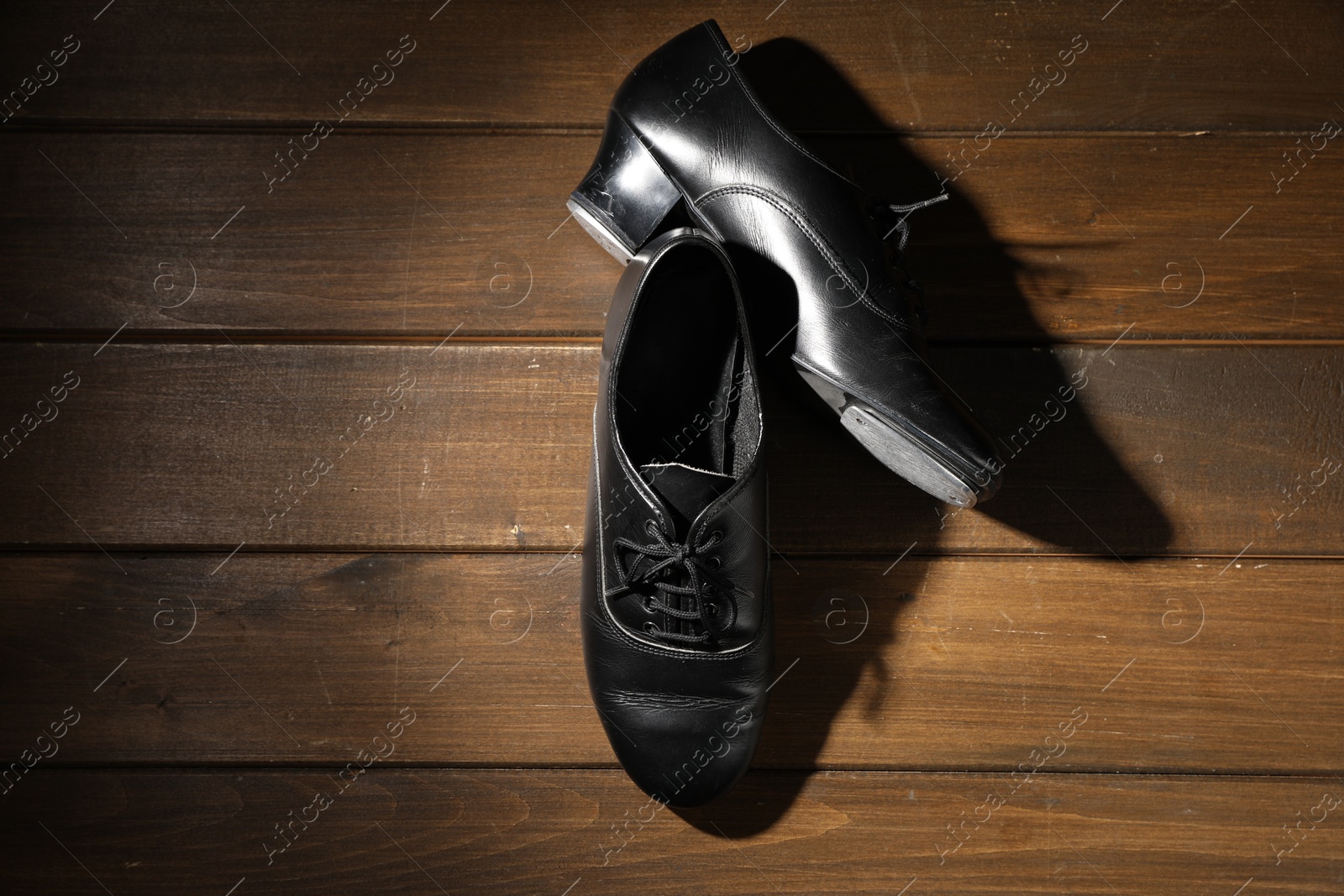 Photo of Pair of tap shoes on wooden floor, top view. Tap dance