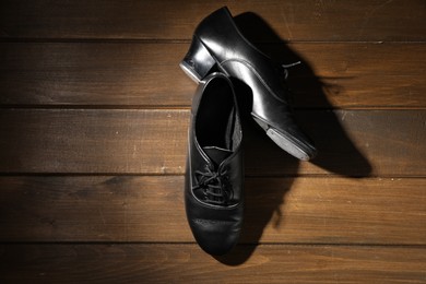 Photo of Pair of tap shoes on wooden floor, top view. Tap dance