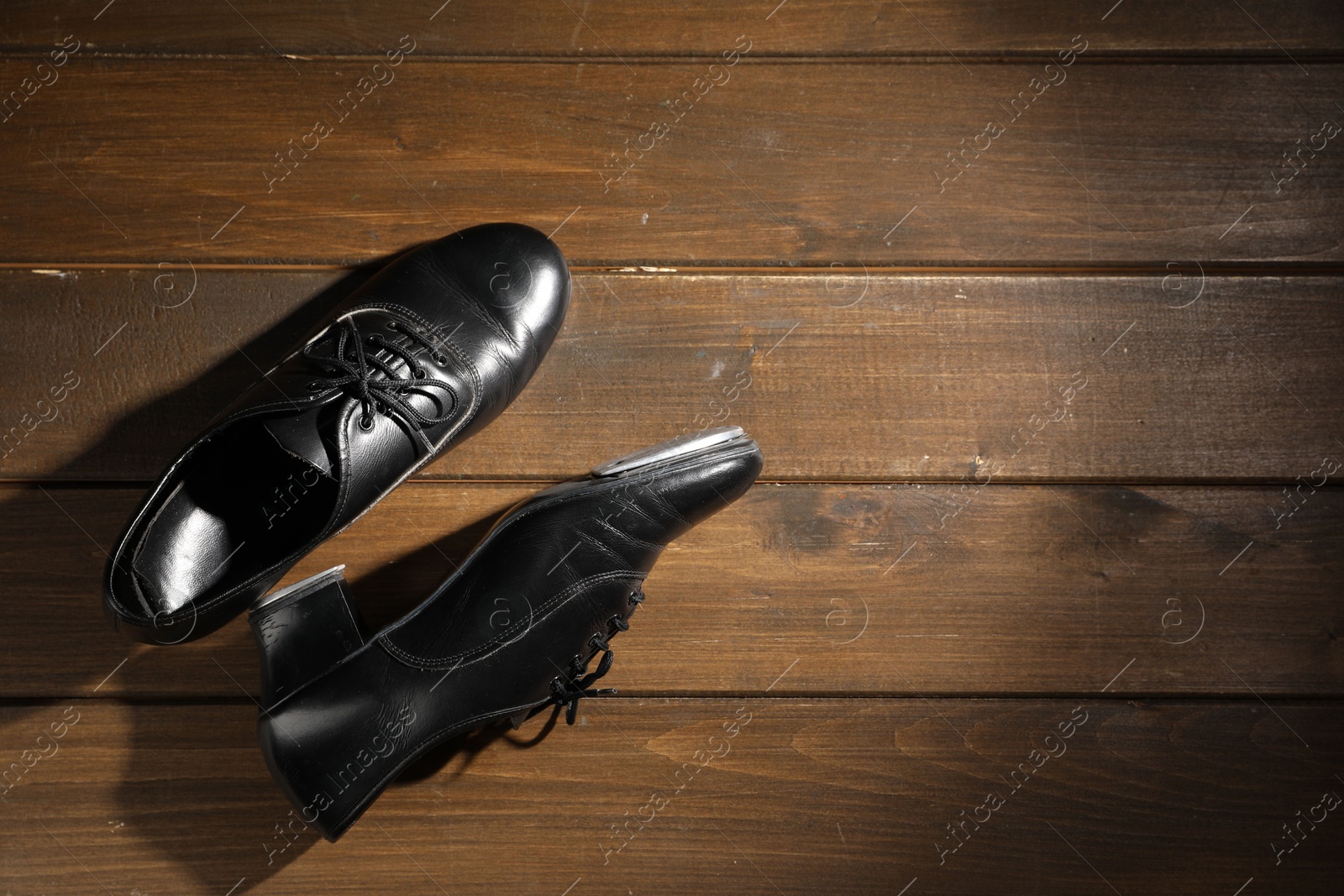 Photo of Pair of shoes for tap dance on wooden floor, top view. Space for text