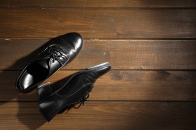 Photo of Pair of shoes for tap dance on wooden floor, top view. Space for text