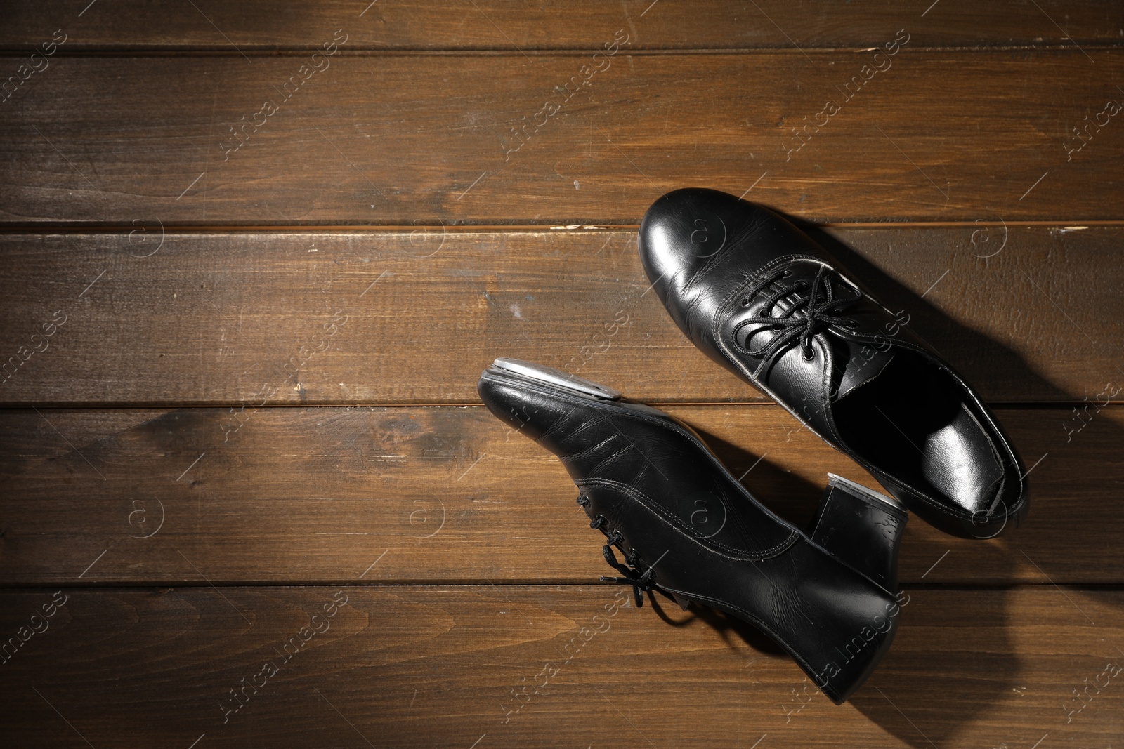 Photo of Pair of shoes for tap dance on wooden floor, top view. Space for text