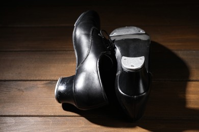 Photo of Pair of tap shoes on wooden floor, closeup. Tap dance