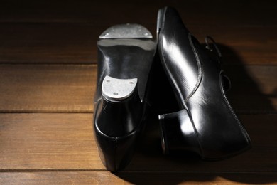 Photo of Pair of tap shoes on wooden floor, closeup. Tap dance