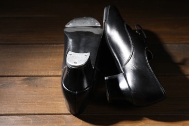 Photo of Pair of tap shoes on wooden floor, closeup. Tap dance