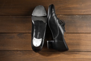 Photo of Pair of tap shoes on wooden floor, top view. Tap dance