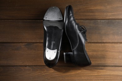Photo of Pair of tap shoes on wooden floor, top view. Tap dance