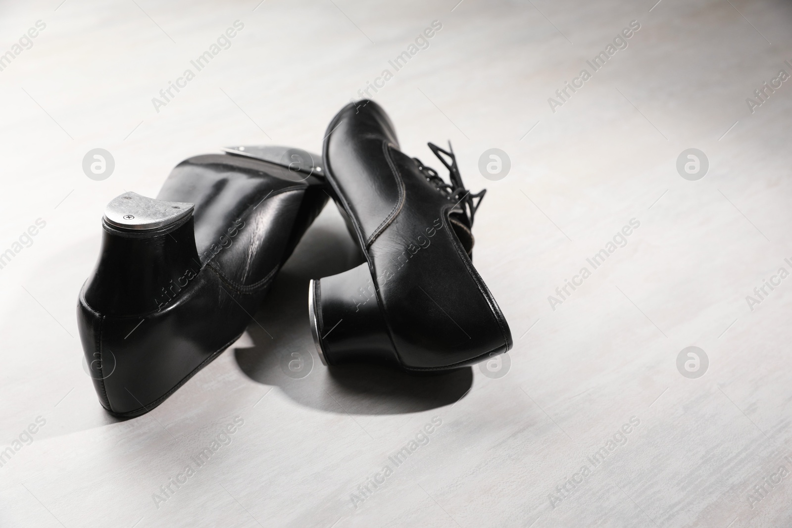 Photo of Pair of shoes for tap dance on white wooden floor. Space for text
