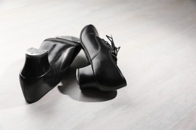 Photo of Pair of shoes for tap dance on white wooden floor. Space for text