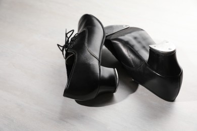Photo of Pair of shoes for tap dance on white wooden floor, closeup