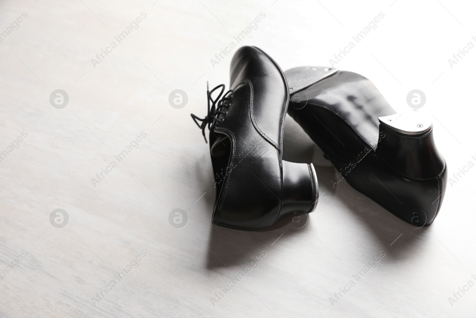Photo of Pair of shoes for tap dance on white wooden floor. Space for text