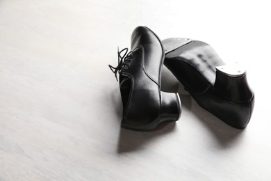 Photo of Pair of shoes for tap dance on white wooden floor. Space for text