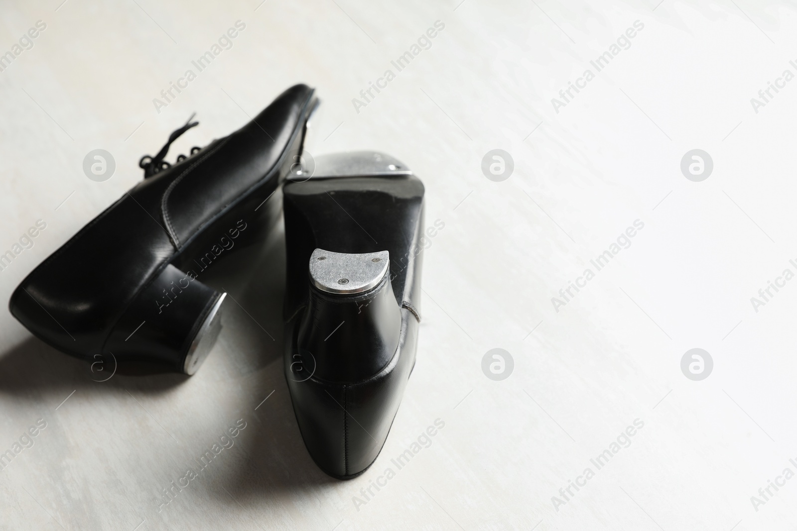 Photo of Pair of shoes for tap dance on white wooden floor, closeup. Space for text