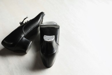 Photo of Pair of shoes for tap dance on white wooden floor, closeup. Space for text