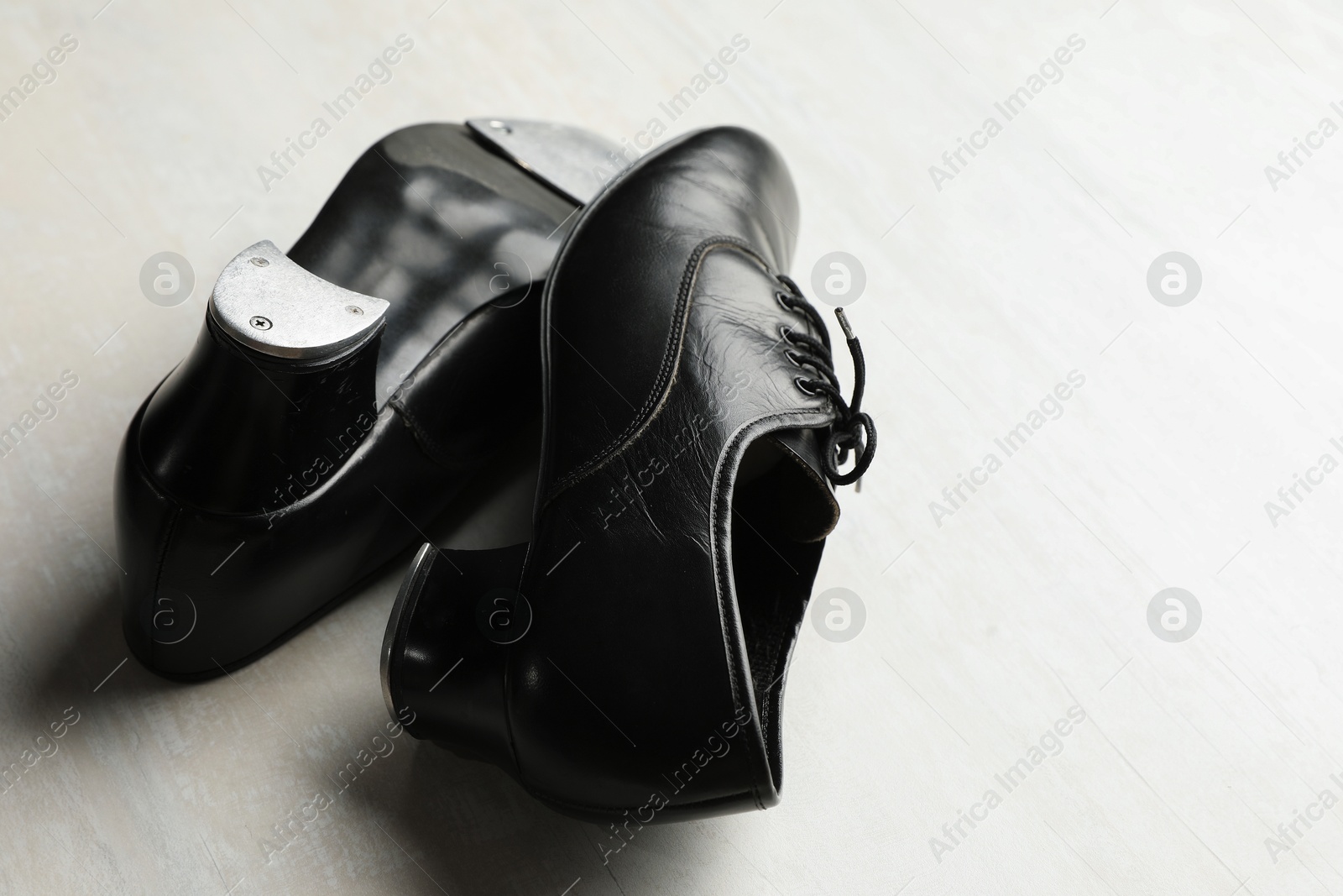Photo of Pair of shoes for tap dance on white wooden floor, closeup. Space for text
