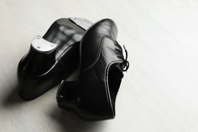 Photo of Pair of shoes for tap dance on white wooden floor, closeup. Space for text