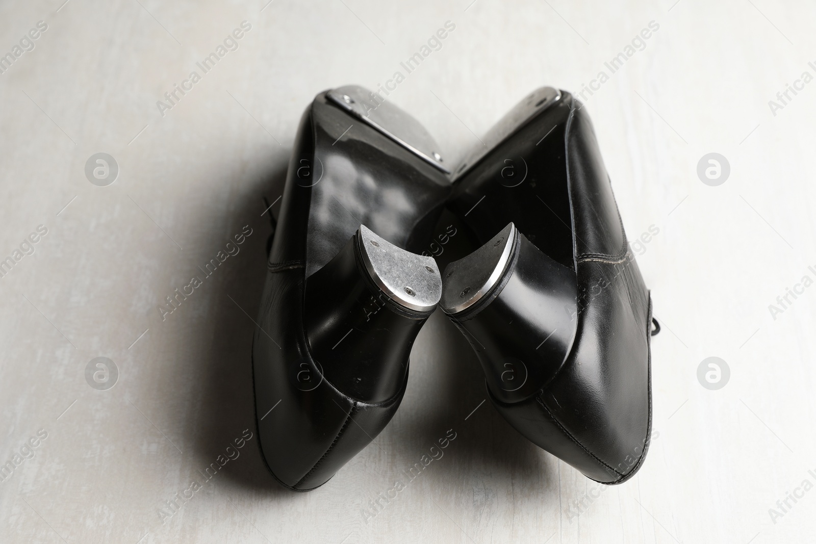 Photo of Pair of shoes for tap dance on white wooden floor, closeup