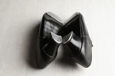 Photo of Pair of shoes for tap dance on white wooden floor, closeup