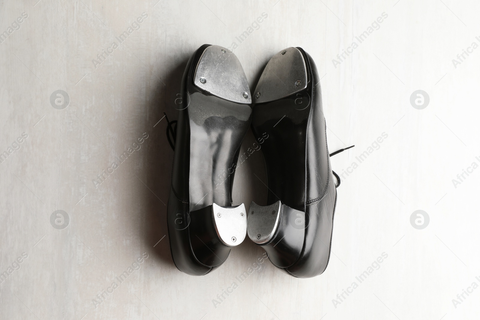 Photo of Pair of shoes for tap dance on white wooden floor, top view