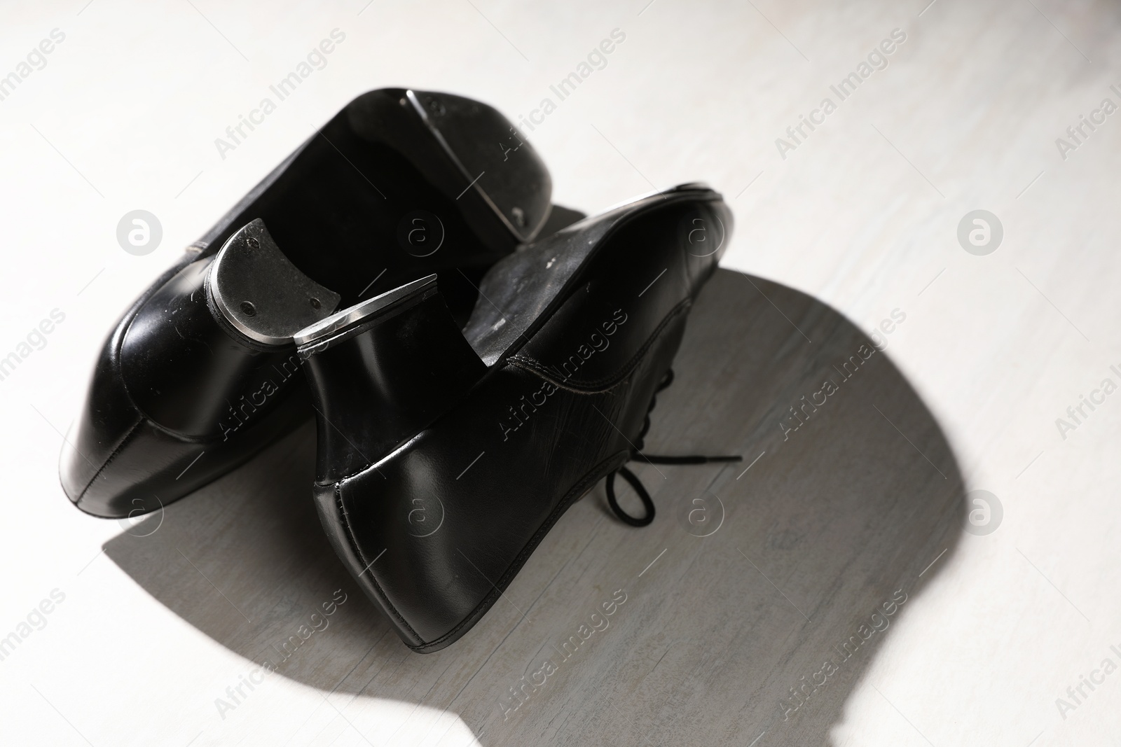 Photo of Pair of shoes for tap dance on white wooden floor, closeup. Space for text