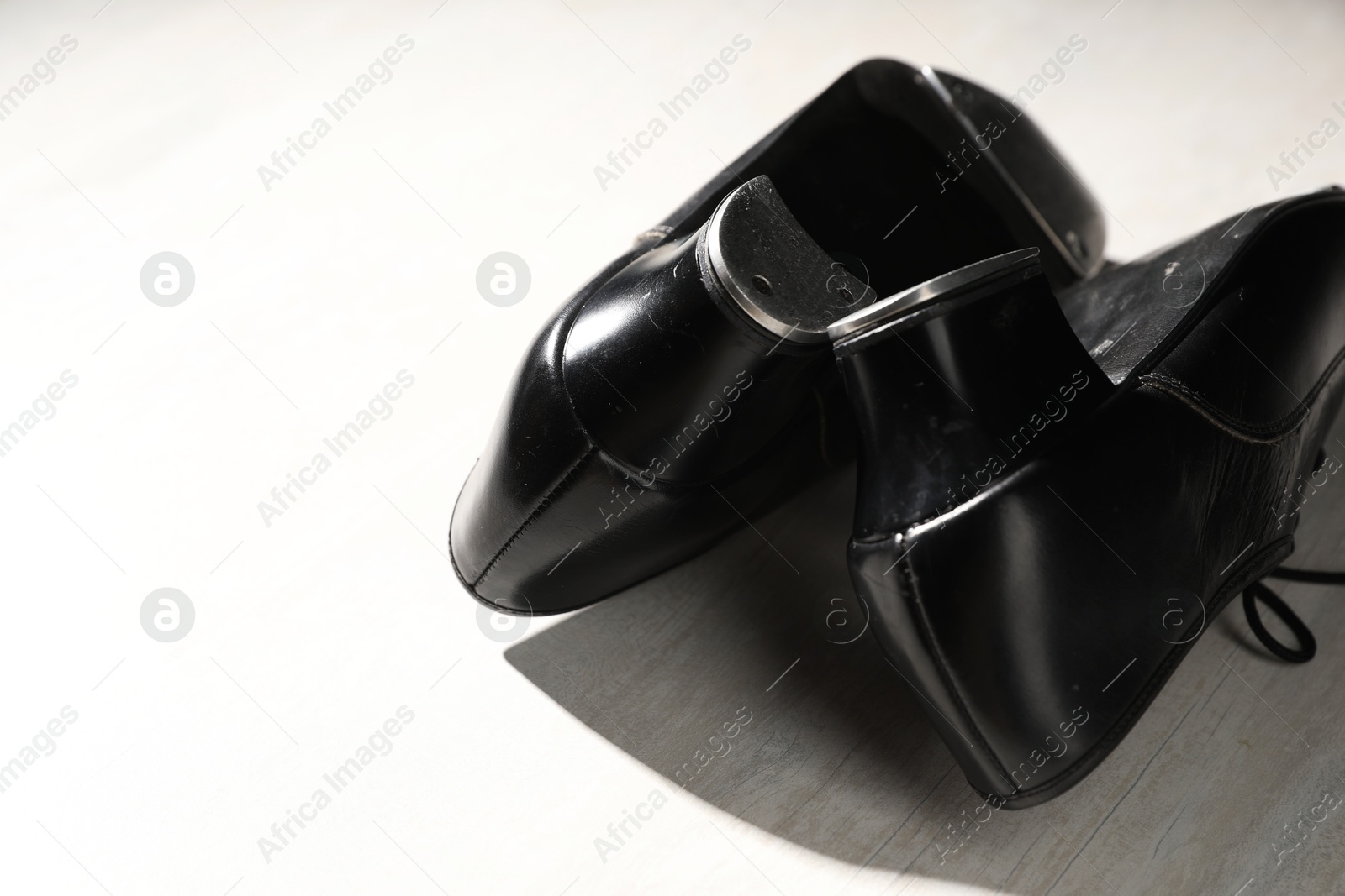 Photo of Pair of shoes for tap dance on white wooden floor, closeup. Space for text