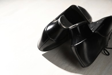 Photo of Pair of shoes for tap dance on white wooden floor, closeup. Space for text
